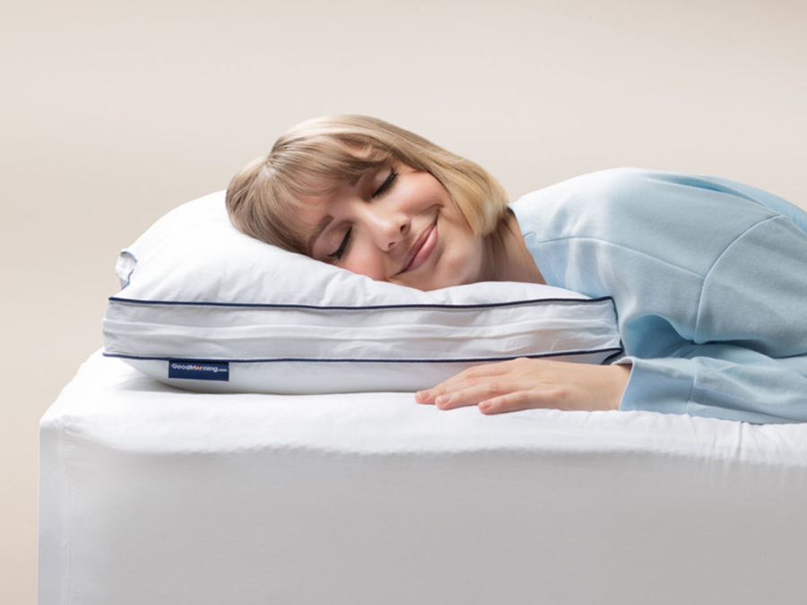 Woman in light blue pajamas peacefully sleeping on her side, head resting on the Adjustable Memory Foam Pillow