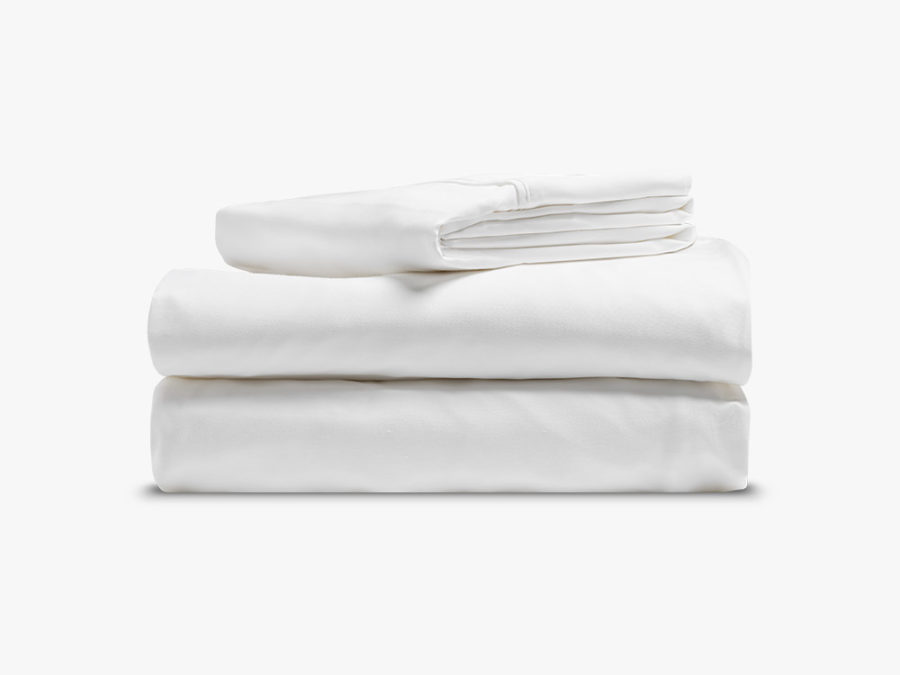 Two pillow cases sit on top of a fitted sheet and a flat sheet, neatly folded with a white background.
